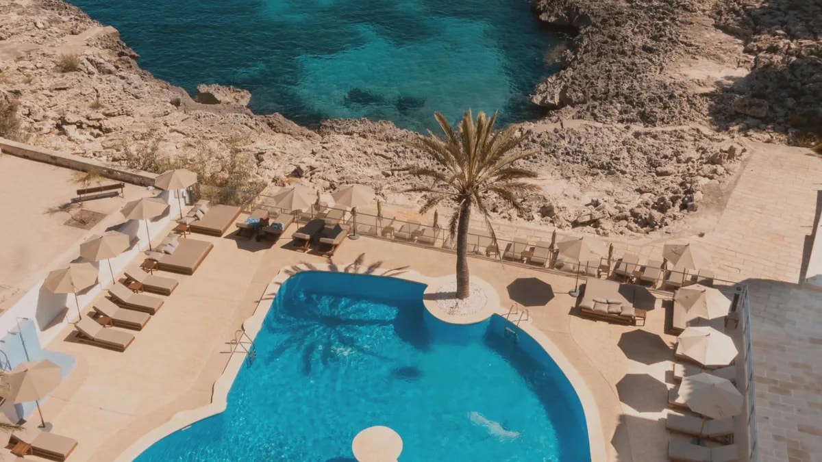 A poolside terrace with parasols above a rocky coastal cove